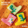 Botas rosa, amarilla y verde sobre superficie naranja. 