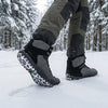 Hombre caminando en la nieve con botas barefoot Saguaro Vitality V gris, demostrando resistencia y agarre en climas extremos.