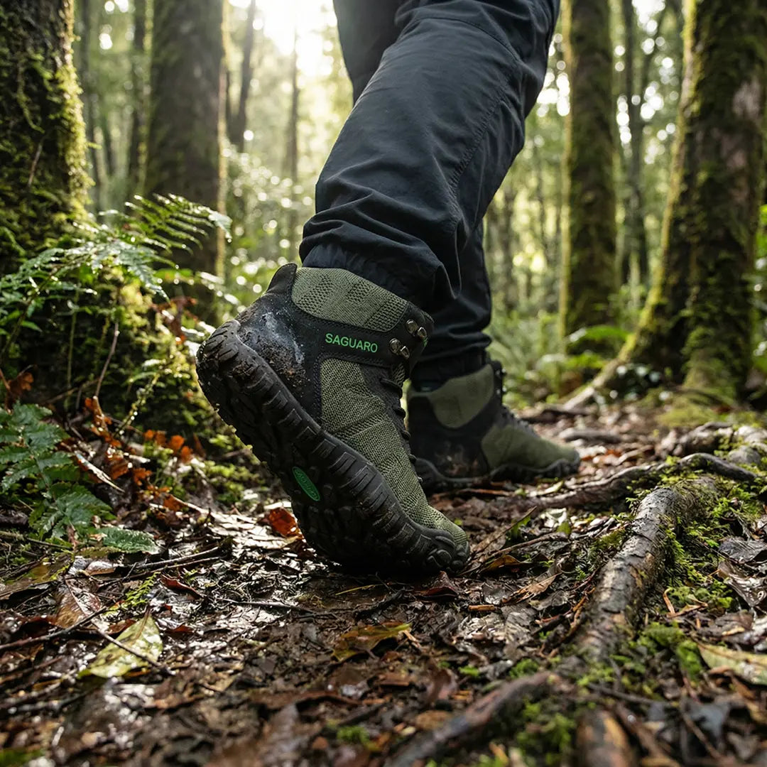 Hombre usando botas de trekking minimalistas Saguaro Vitality V verde militar, resistencia y comodidad para senderismo intenso.