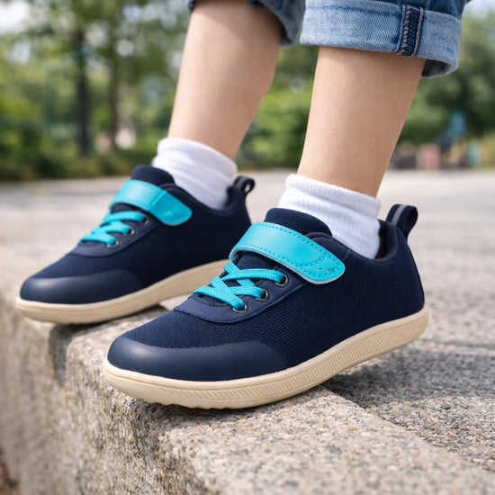 Niño saltando con zapatillas anchas infantiles azul marino que protegen el desarrollo del pie.